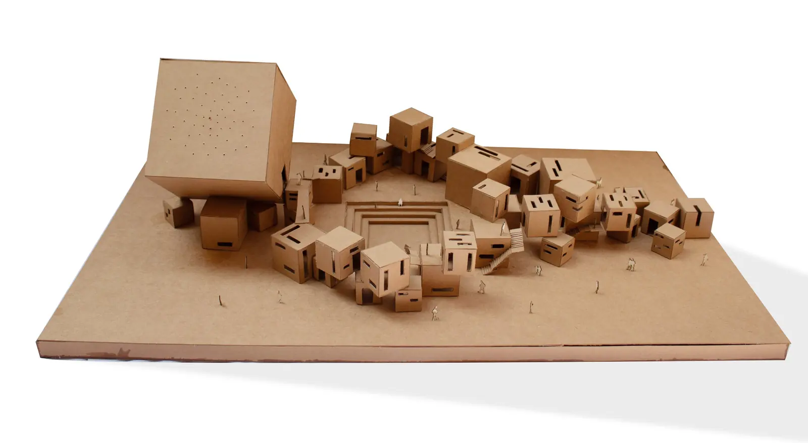 Cardboard concept model: clusters of small cubes with punched openings stepping up to a large tilted cube around a sunken square court